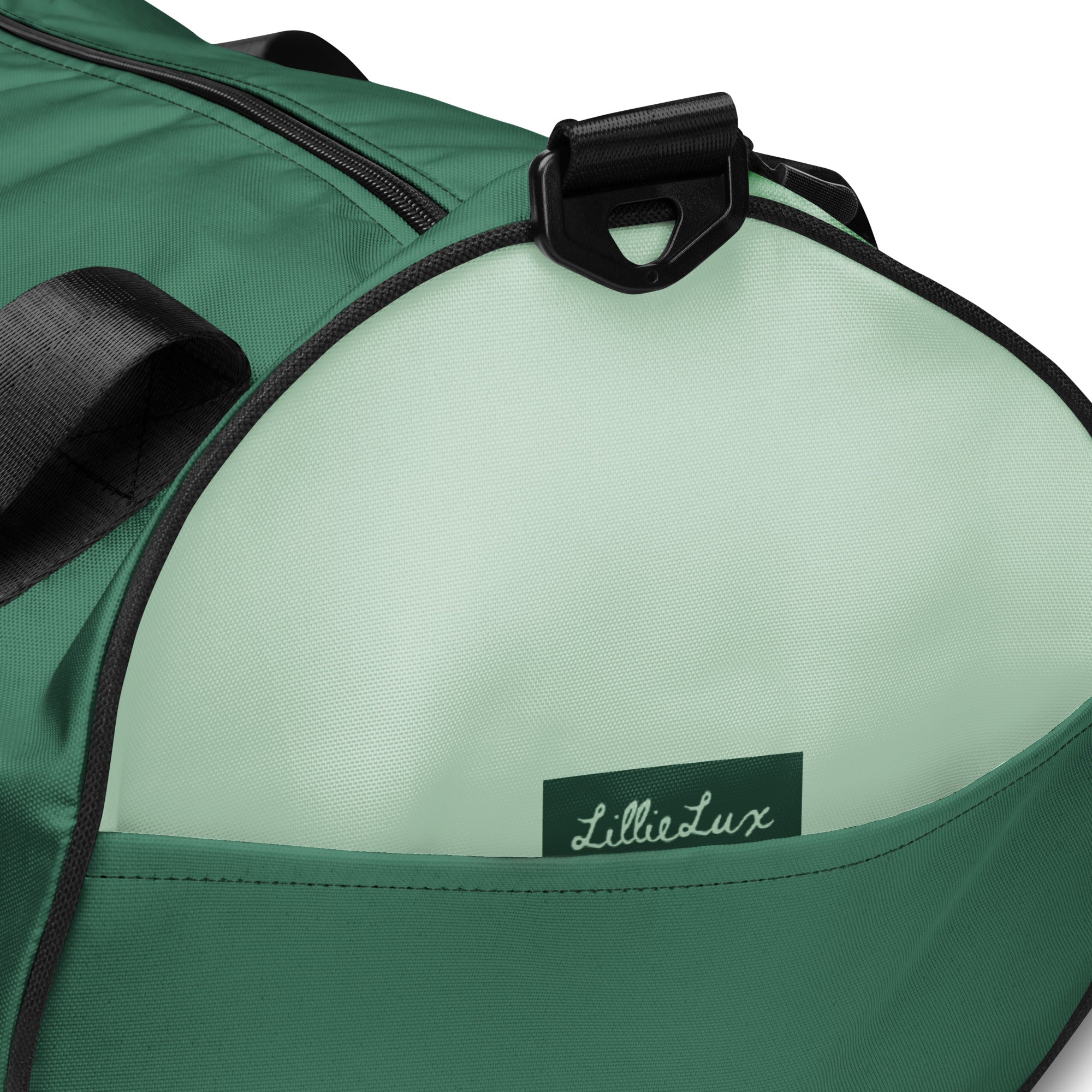 Close-up of the LillieLux Sage gym bag in muted green tones with black straps and signature logo patch.